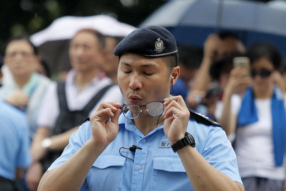 A police officer tries to clean his glasses during a rally outside Legislative Council Complex in Hong Kong, Sunday, June 30, 2019. Pro-China's supporters rallied in support of the police at Tamar Park (AP Photo/Kin Cheung)