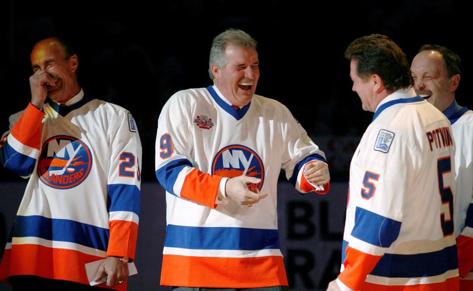 FILE - Clark Gillies, second from left, greets Denis Potvin, second from right, as Bryan Trottier, right, and Bobby Nystrom, left, get a chuckle out of the encounter during introductions for "The Core of the Four" New York Islanders teams that won consecutive Stanley Cups from 1979 to 1982, at Nassau Coliseum in Uniondale, N.Y., March 2, 2008. Gillies has died. He was 67. The Islanders announced Gillies' death Friday night, with team president and general manager Lou Lamoriello saying “the entire Islanders community is devastated by the loss.” The team did not say where Gillies died or provide a cause of death. (AP Photo/Kathy Willens, File)