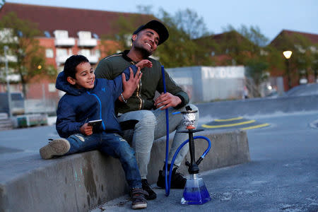 Mudasir Khan, originally from Pakistan, sits with his nephew Yaeesh Rao Khan in Mjolnerparken, a housing estate that features on the Danish government's "Ghetto List", in Copenhagen, Denmark, May 2, 2018. REUTERS/Andrew Kelly