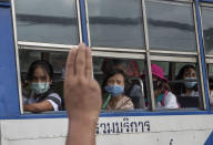 A pro-democracy protester flashes a three-fingered salute, the movement's symbol of resistance, as bus passengers watch during a protest outside the Parliament in Bangkok, Thailand, Thursday, Sept. 24, 2020. Lawmakers in Thailand are expected to vote Thursday on six proposed amendments to the constitution, as protesters supporting pro-democratic charter reforms gathered outside the parliament building. (AP Photo/Gemunu Amarasinghe)