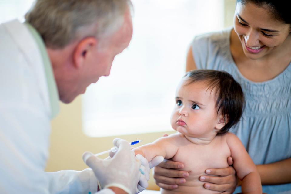 baby looking at doctor about to inject vaccine