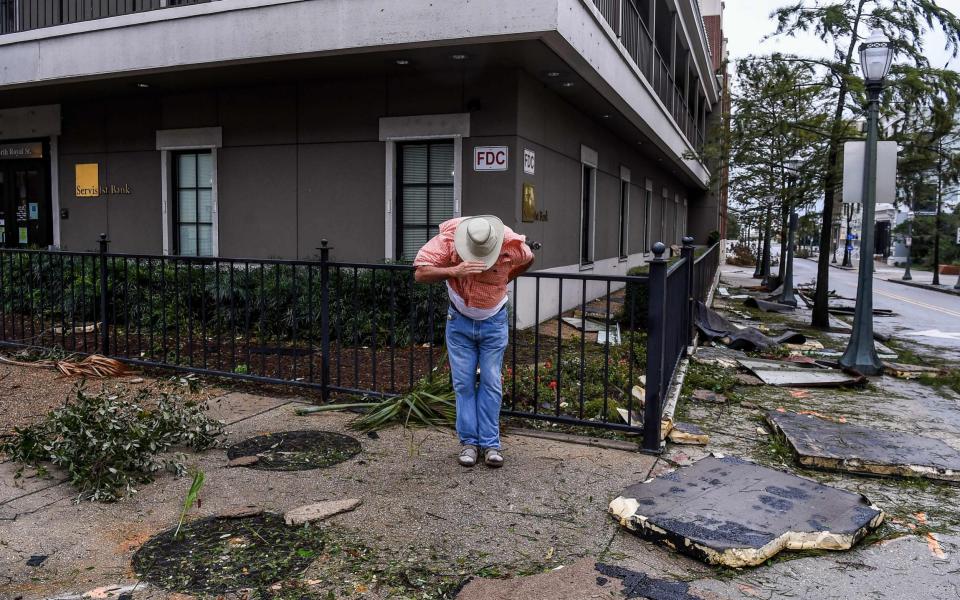 A man in Mobile, Alabama, clings on to his hat in high winds - CHANDAN KHANNA /AFP