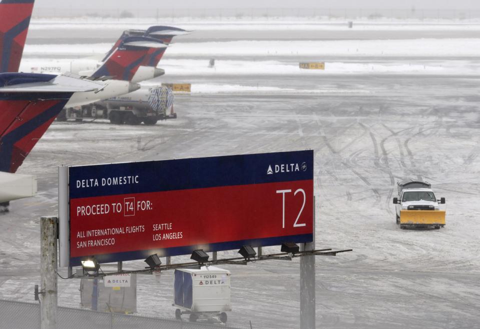 A snowplow makes its way on a slushy patch between two terminals after a Delta flight from Toronto to New York skidded off the runway into snow at Kennedy International Airport, temporarily halting all air travel into and out of the airport, Sunday, Jan. 5, 2014, in New York. (AP Photo/Kathy Willens)