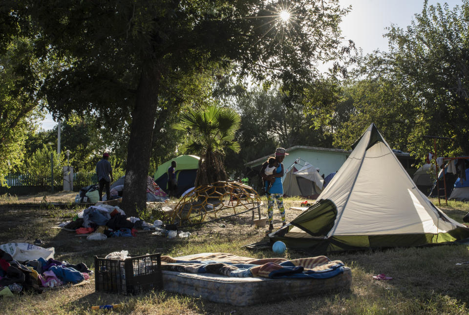 A migrant holds a child at an encampment in Ciudad Acuna, Mexico, Friday, Sept. 24, 2021, across the Rio Grande from Del Rio, Texas. No migrants remained Friday at the Texas border encampment in Del Rio where almost 15,000 people — most of them Haitians — had converged just days earlier seeking asylum, local and federal officials said. (AP Photo/Felix Marquez)