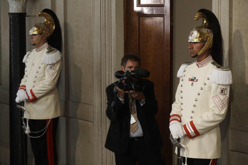 A cameraman films the corassiers standing guard at the entrance of the office door of Italy's President Sergio Mattarella, in Rome, Wednesday, Aug. 21, 2019. One day after Giuseppe Conte resigned as premier, President Mattarella started receiving political leaders to explore options for the way forward. (AP Photo/Gregorio Borgia)