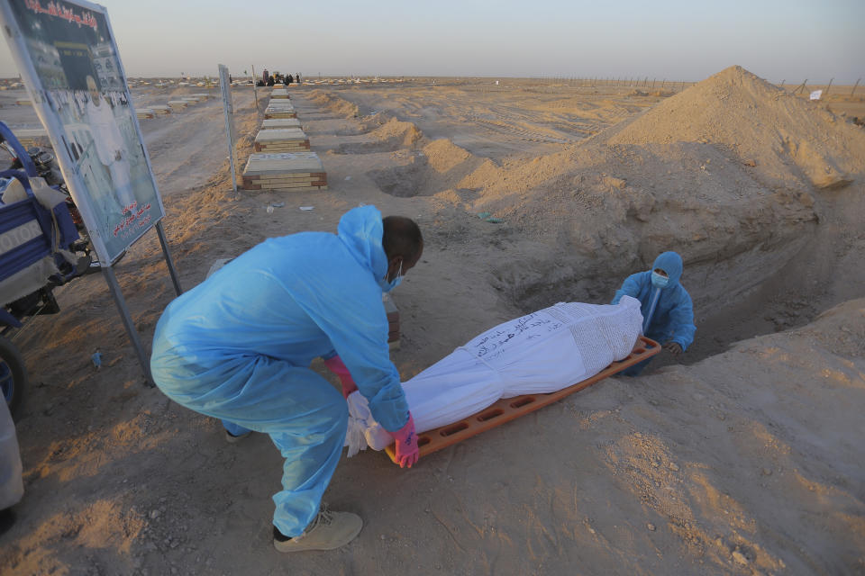 Members of the Shiite Imam Ali brigades militia bury a body of a coronavirus victim during a funeral at Wadi al-Salam cemetery near Najaf, Iraq, Monday, July 20, 2020. A special burial ground near the Wadi al-Salam cemetery has been created specifically for COVID-19 victims since rejections of such burials have continued in Baghdad cemeteries and elsewhere in Iraq. (AP Photo/Anmar Khalil)