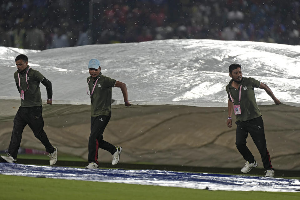 Groundsmen run to cover the ground as rain interrupts the Indian Premier League cricket match between Punjab Kings and Royal Challengers Bengaluru in Dharamshala, India, Thursday, May 9, 2024. (AP Photo /Ashwini Bhatia)