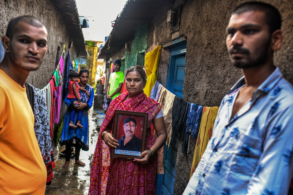 Kashinath Kale's widow, Sangeeta, flanked by her sons Akshay, left, and Avinash, holds a framed portrait of her late husband outside their home in Kalewadi, a suburb of Pune. Kale, 44, died from COVID-19 in July as the family desperately tried to find a hospital bed with a ventilator.<span class="copyright">Atul Loke for TIME</span>