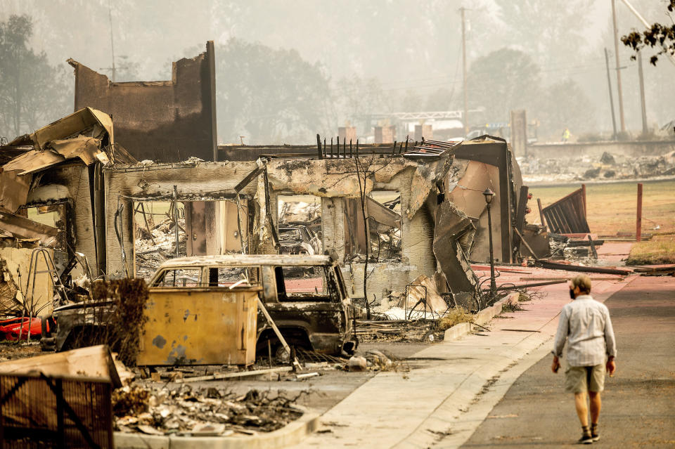 A man examines residences destroyed by the Almeda Fire at the Parkview Townhomes in Talent, Ore., on Wednesday, Sept. 16, 2020. (AP Photo/Noah Berger)