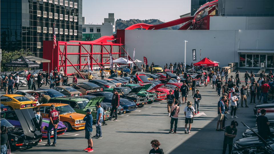 a group of people walking around a car show