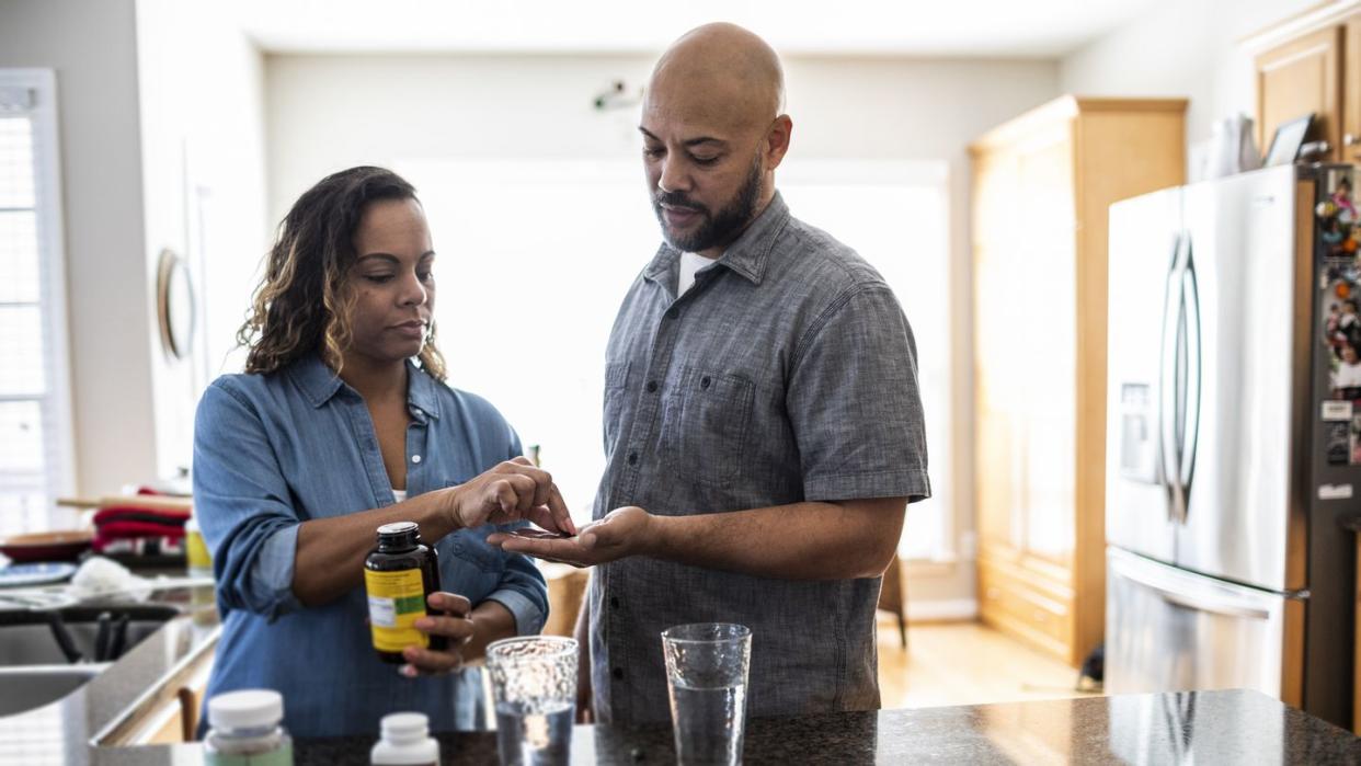 husband and wife taking vitamins at home