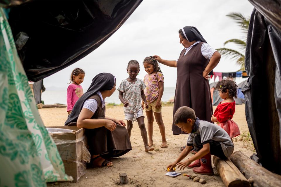 Sister Deissy Viviana Otero Yepez, left, and Sister Digna Gloria Gelpud Mallama visit with children in the migrant camp in Necoclí. | Spenser Heaps, Deseret News
