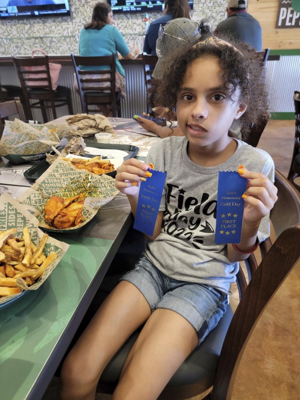 In this image provided by Vincent Salazar, Layla Salazar poses with her first place ribbons from field day at her school, Robb Elementary School. Layla was one of the 19 children and their two teachers who were gunned down behind a barricaded door at Robb Elementary School in Uvalde, Texas. (Vincent Salazar via AP)