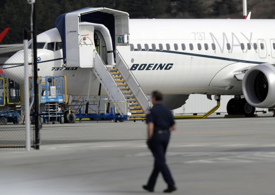 FILE- In this March 14, 2019, file photo a worker walks next to a Boeing 737 MAX 8 airplane parked at Boeing Field in Seattle. U.S. prosecutors are looking into the development of Boeing's 737 Max jets, a person briefed on the matter revealed Monday, the same day French aviation investigators concluded there were "clear similarities" in the crash of an Ethiopian Airlines Max 8 last week and a Lion Air jet in October. (AP Photo/Ted S. Warren, File)