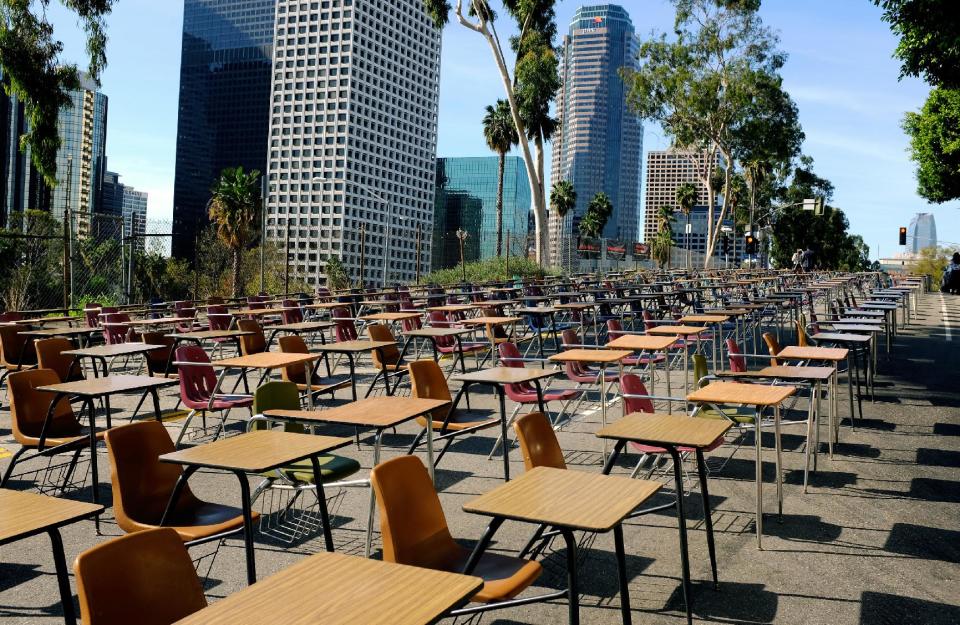 School desks placed by parents, district graduates and activists block a street in front of the Los Angeles Unified School District headquarters in a demonstration against student dropout rates Tuesday, April 8, 2014, in downtown Los Angeles. Protest organizers say the 375 desks are there to represent the 375 students who drop out of the district every week during the school year. (AP Photo/Richard Vogel)