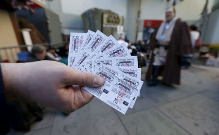 A person shows tickets for the first showing of "Star Wars: The Force Awakens" while waiting in the forecourt of the TCL Chinese Theatre in Hollywood, California December 17, 2015. REUTERS/Mario Anzuoni