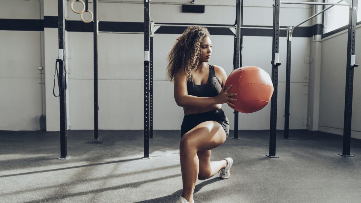 young woman exercising with medicine ball in gym