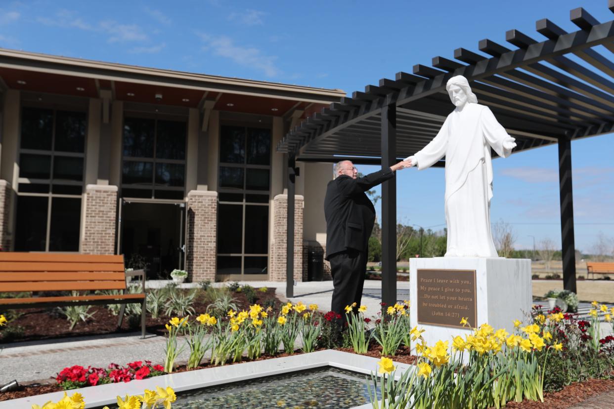 Fr. Joe Smith touches the hand of the statue of Jesus as he blesses the garden and reflecting pool at the St. Joseph's/Candler Richmond Hill campus on Friday, February 23, 2024.