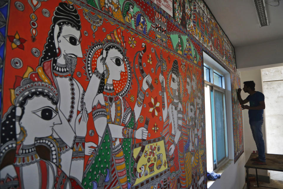 In this Nov. 30, 2018 photo, an Indian artist paints a wall with traditional Mithila art at the newly built Janakpur train station in Nepal from where a new 34 kilometers (21 miles) long rail line runs to Jay Nagar in the Indian state of Bihar. The competition between two Asian giants, India and China, for influence over tiny Nepal is yielding a bonanza in the form of the Himalayan mountain nation’s first modern railway, and possibly more to come.(AP Photo/Niranjan Shrestha)