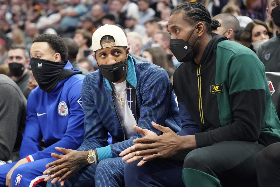 Los Angeles Clippers' Paul George, left, and Kawhi Leonard, right, look on from the bench in the first half during an NBA basketball game against the Utah Jazz Wednesday, Dec. 15, 2021, in Salt Lake City. (AP Photo/Rick Bowmer)