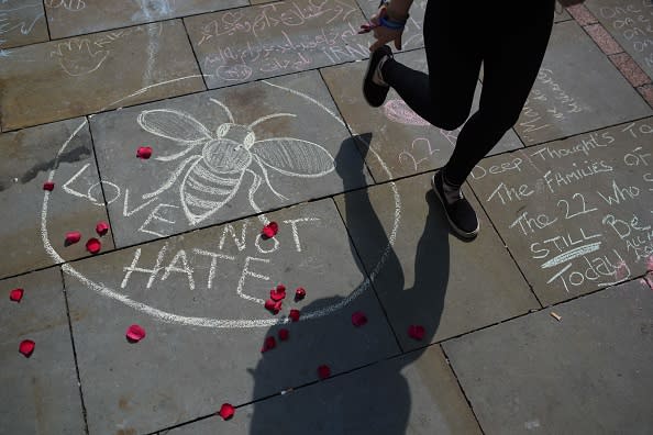 A person walks past a chalk message reading ‘Love not Hate’ in St Ann’s Square in Manchester, northwest England on May 25, 2017, placed in tribute to the victims of the May 22 terror attack at the Manchester Arena. Last year, a suicide bombing ripped into young fans at an Ariana Grande concert at the Manchester Arena on May 22. The Islamic State group claimed responsibility for the carnage. (Photo credit: OLI SCARFF/AFP/Getty Images)