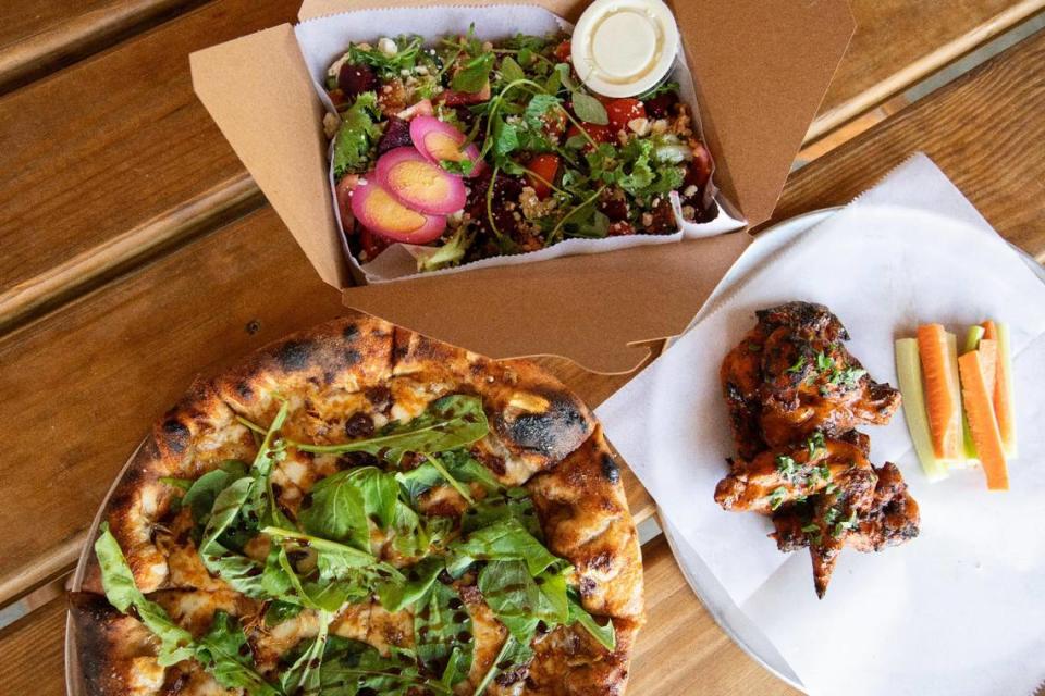 The Umami Mama pizza made with local chicken, bacon, mozzarella, caramelized onions and fresh arugula and kalamata olives along with Locals Wings and Kentucky Cobb salad at Locals Food Hub & Pizza Pub in Frankfort, Ky., June 16, 2023.