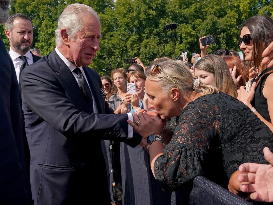 A woman kisses King Charles III's hand outside Buckingham Palace on September 9, 2022.