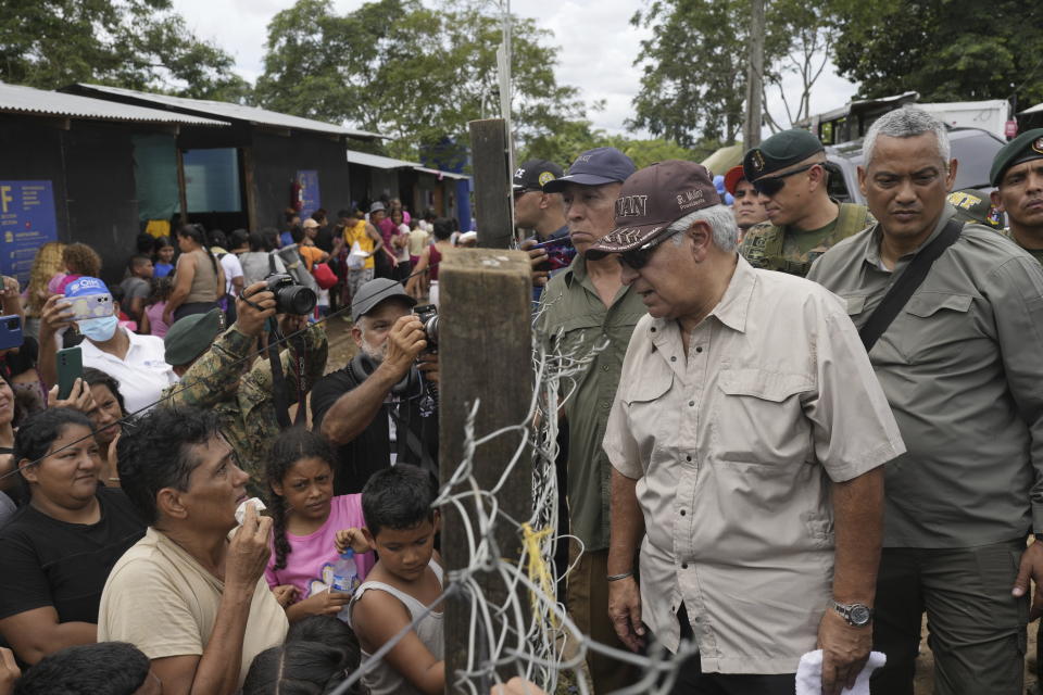 Panamanian President-elect Jose Raul Mulino speaks with a Venezuelan migrant, left, and other migrants at a camp after they walked across the Darien Gap from Colombia, in Lajas Blancas, Panama, Friday, June 28, 2024. (AP Photo/Matias Delacroix)