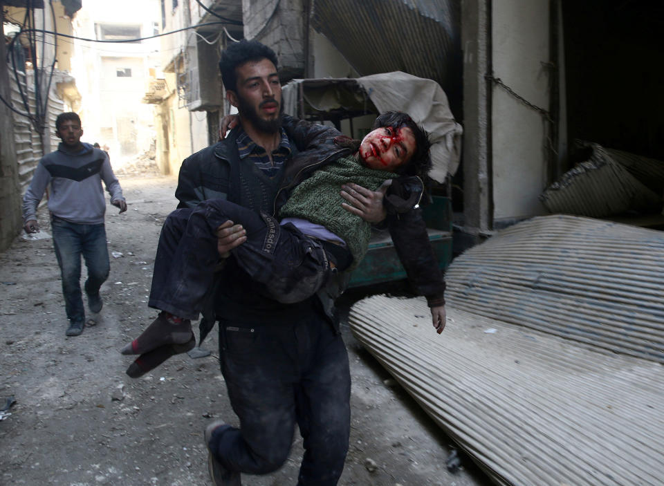 <p>Mohammed Abu Anas runs with an injured boy in the besieged eastern Ghouta town of Hamouriyeh near Damascus, Syria, Feb. 21, 2018. (Photo: Bassam Khabieh/Reuters) </p>