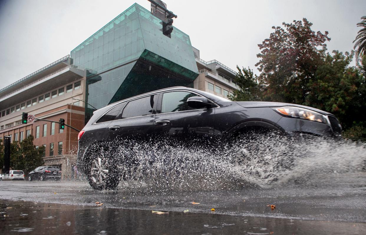 A car splashes through a puddle left by the first rain of the season on Weber Avenue near San Joaquin Street in downtown Stockton on Tuesday, Nov. 1, 2022.