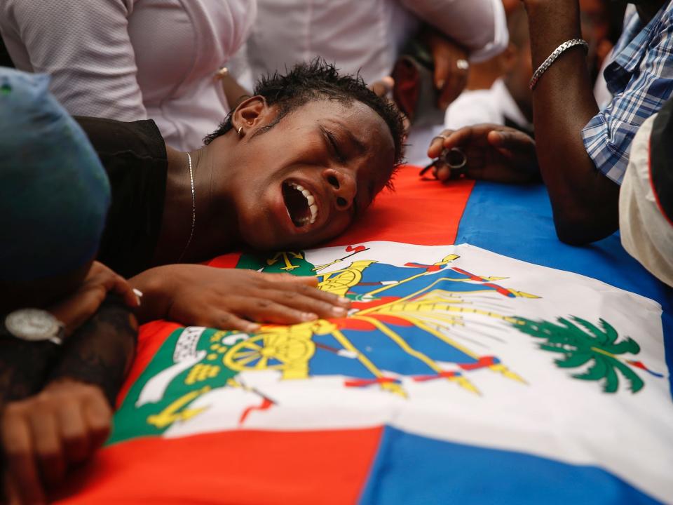 A woman cries on the Haitian flag-draped coffin of a 16-year-old boy killed during a month of demonstrations aimed at ousting President Jovenel Moïse, during a joint funeral for two victims at a public plaza near the National Palace in Port-au-Prince, Haiti, Wednesday, Oct. 16, 2019.