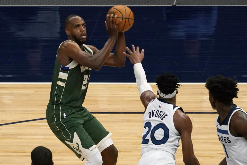 Milwaukee Bucks' Khris Middleton, left, eyes the basket as Minnesota Timberwolves' Josh Okogie rushes in during the second half of an NBA basketball game Wednesday, April 14, 2021, in Minneapolis. Middleton led his team's scoring as the Bucks won 130-105. (AP Photo/Jim Mone)