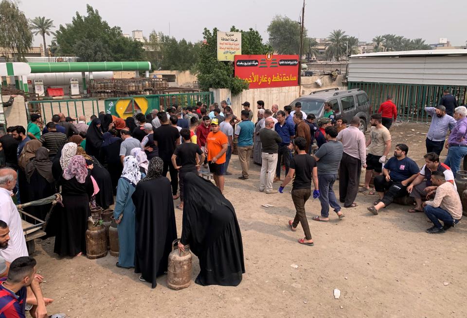 Iraqis wait to buy cooking gas canisters in downtown Baghdad, Iraq Monday, March 16, 2020. Iraq announced a weeklong curfew late Sunday. People raced to supermarkets and swiftly emptied shelves, while others stocked up on cooking fuel. The curfew, which is set to begin late Tuesday, includes the suspension of all flights from Baghdad's international airport. (AP Photo/Ali Abdul Hassan)