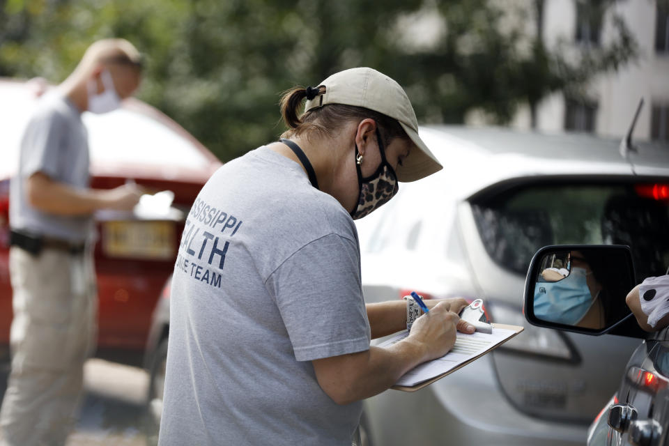 Members of the Mississippi Health Response Team take down medical information from people potentially affected by COVID-19 incidences at the Mississippi Legislature at the Capitol in Jackson, Miss., Monday, July 6, 2020. House Speaker Philip Gunn confirmed Sunday that he had recently tested positive for COVID-19. A makeshift drive-thru testing center was set in place on Capitol grounds. (AP Photo/Rogelio V. Solis)