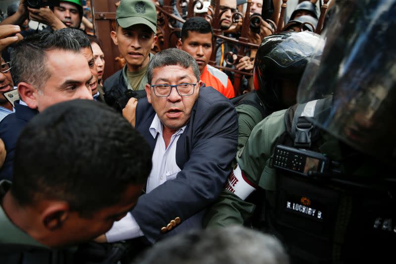 Venezuelan lawmaker Avilio Troconiz tries to pass through members of the security forces at the National Assembly building in Caracas