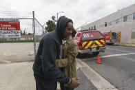 English actress and singer Aimée Osbourne, who creates electropop music under the name ARO, right, hugs music producer Jamal Rajad Davis, outside a Hollywood recording studio in Los Angeles Friday, May 20, 2022 in Los Angeles. Ozzy Osbourne's daughter Aimee and her producer escaped a Hollywood recording studio fire that killed another person, her mother said. (AP Photo/Damian Dovarganes)