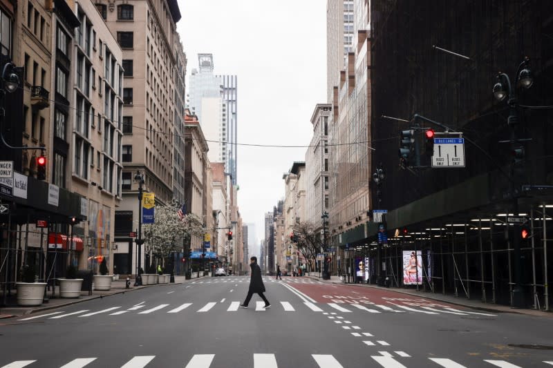 A man crosses a nearly empty 5th Avenue in midtown Manhattan during the outbreak of the coronavirus disease (COVID-19) in New York