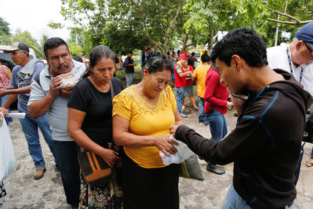 Relatives of victims of the eruption of the Fuego volcano receive food from volunteers outside the morgue of Escuintla, Guatemala 7 June, 2018. REUTERS/Luis Echeverria