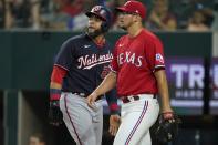 Washington Nationals' Nelson Cruz, left, walks past Texas Rangers starting pitcher Dane Dunning, right, on his way to the dugout after being thrown out at home while trying to score on a Keibert Ruiz single in the fourth inning of a baseball game, Friday, June 24, 2022, in Arlington, Texas. (AP Photo/Tony Gutierrez)