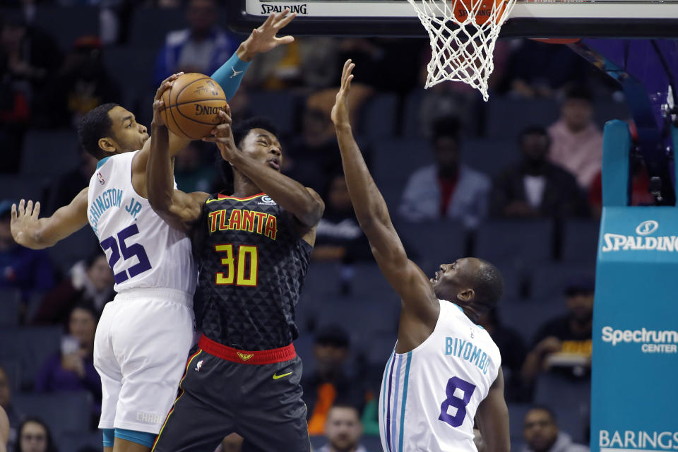 Atlanta Hawks' Damian Jones (30) tries to score as his shot is rejected by Charlotte Hornets' P.J. Washington (25) and Bismack Biyombo (8) during the first half of an NBA basketball game in Charlotte, N.C., Sunday, Dec. 8, 2019. (AP Photo/Bob Leverone)