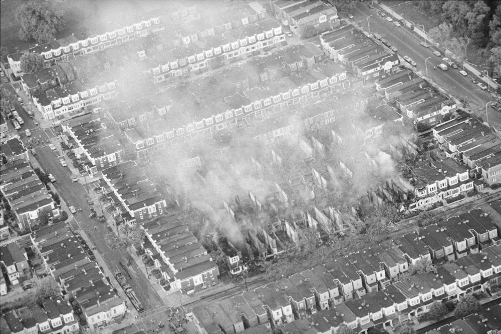 In this May 14, 1985, file photo, smoke rises from the ashes of a West Philadelphia neighborhood the morning after a siege between Philadelphia police and members of the radical group MOVE left 11 people dead and 61 homes destroyed. (AP Photo/Peter Morgan, File)