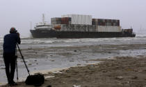 A cameraman films the stranded Heng Tong 77 cargo ship at Sea View Beach near the southern port city of Karachi, Pakistan, Monday, July 26, 2021. Pakistani authorities said they are working on plans to refloat the cargo ship that ran aground last week amid bad weather en route to Istanbul from China. (AP Photo/Fareed Khan)