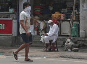 A man walks past a vendor reading a newspaper in Hyderabad, India, Saturday, July 11, 2020. In just three weeks, India went from the world’s sixth worst-affected country by the coronavirus to the third, according to a tally by Johns Hopkins University. India's fragile health system was bolstered during a stringent monthslong lockdown but could still be overwhelmed by an exponential rise in infections. (AP Photo/Mahesh Kumar A.)