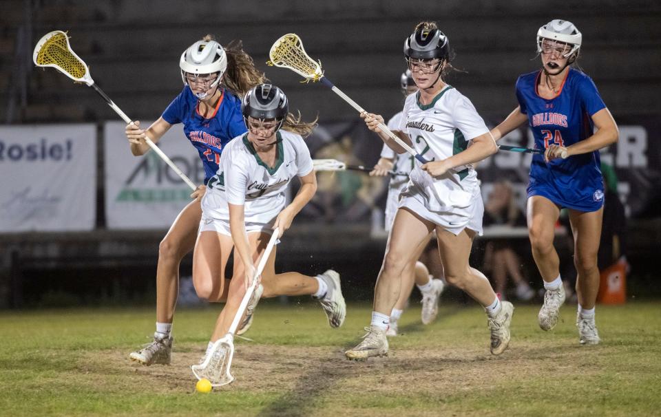 Catholic's Collier Brown (No. 9) scoops up a loose ball as the Bolles High defenders give chase during Friday's District 1-A girls' lacrosse semi-finals match.