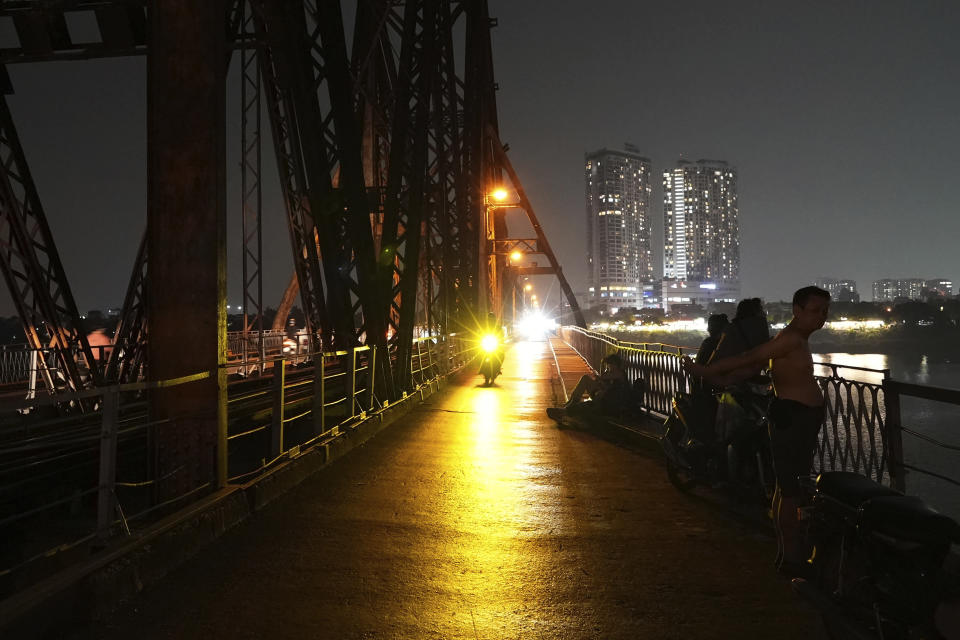 People rest on a bridge for cool breeze in Hanoi, Vietnam, on June 8, 2023. Vietnam has released a long-anticipated energy plan meant to take the country through the next decade and help meet soaring demand while reducing carbon emissions. (AP Photo/Hau Dinh)