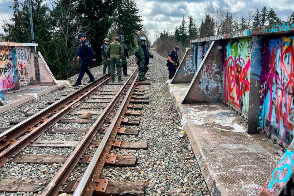 Deputies from the Pierce County Sheriff’s Department inspect the scene where a man reportedly holding a grenade was shot by a deputy on the train tracks near 112th Street East in Midland on Friday, March 24, 2023.