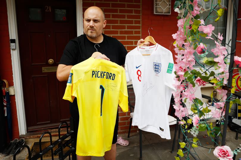 Chris Dowse poses for photos with two signed England shirts