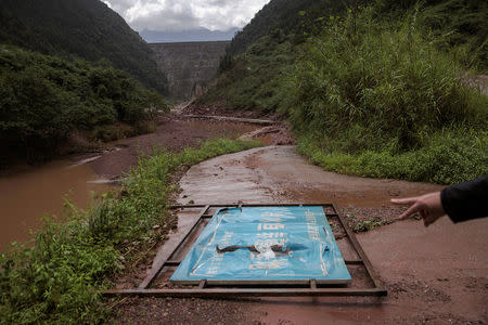 A sign for a fish breeding base run by a local poverty relief and migration work bureau is seen under one of the dams on the Zhougong River near Ya'an in Sichuan province, China, August 4, 2018. REUTERS/Damir Sagolj