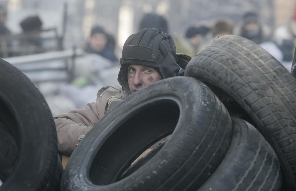 A protester guards the barricades in front of riot police in Kiev, Ukraine, Monday, Jan. 27, 2014. Ukraine's justice minister is threatening to call for a state of emergency unless protesters leave her ministry building, which they occupied during the night. The seizure of the building early Monday underlined how anti-government demonstrators are increasingly willing to take dramatic action as they push for the president's resignation and other concessions. Protesters now occupy four sizable buildings in downtown Kiev, including the city hall. (AP Photo/Efrem Lukatsky)