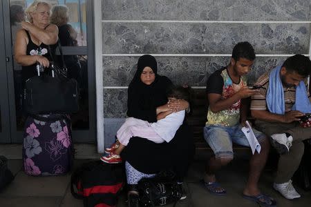 A Syrian refugee woman holds a baby as she waits for a train to take them to the northern city of Thessaloniki, in Athens, Greece, August 20, 2015. REUTERS/Alkis Konstantinidis